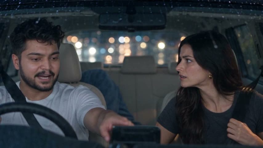 Deep at the wheel of his SUV, turning to Nora.